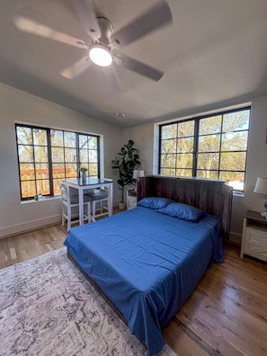 Une chambre à coucher avec un lit, un bureau et deux fenêtres.