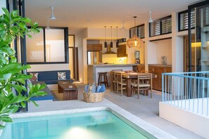 A modern kitchen with a dining area, a pool, and a seating area with a view.