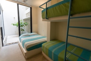 A room with bunk beds, a sliding door, a plant, and a small outdoor area with a gravel path. - Villa w/ 800sqft terrace & pool (Puerto Escondido)