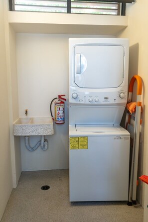 A compact laundry room with a washing machine, a sink, and a fire extinguisher. - Villa w/ 800sqft terrace & pool (Puerto Escondido)