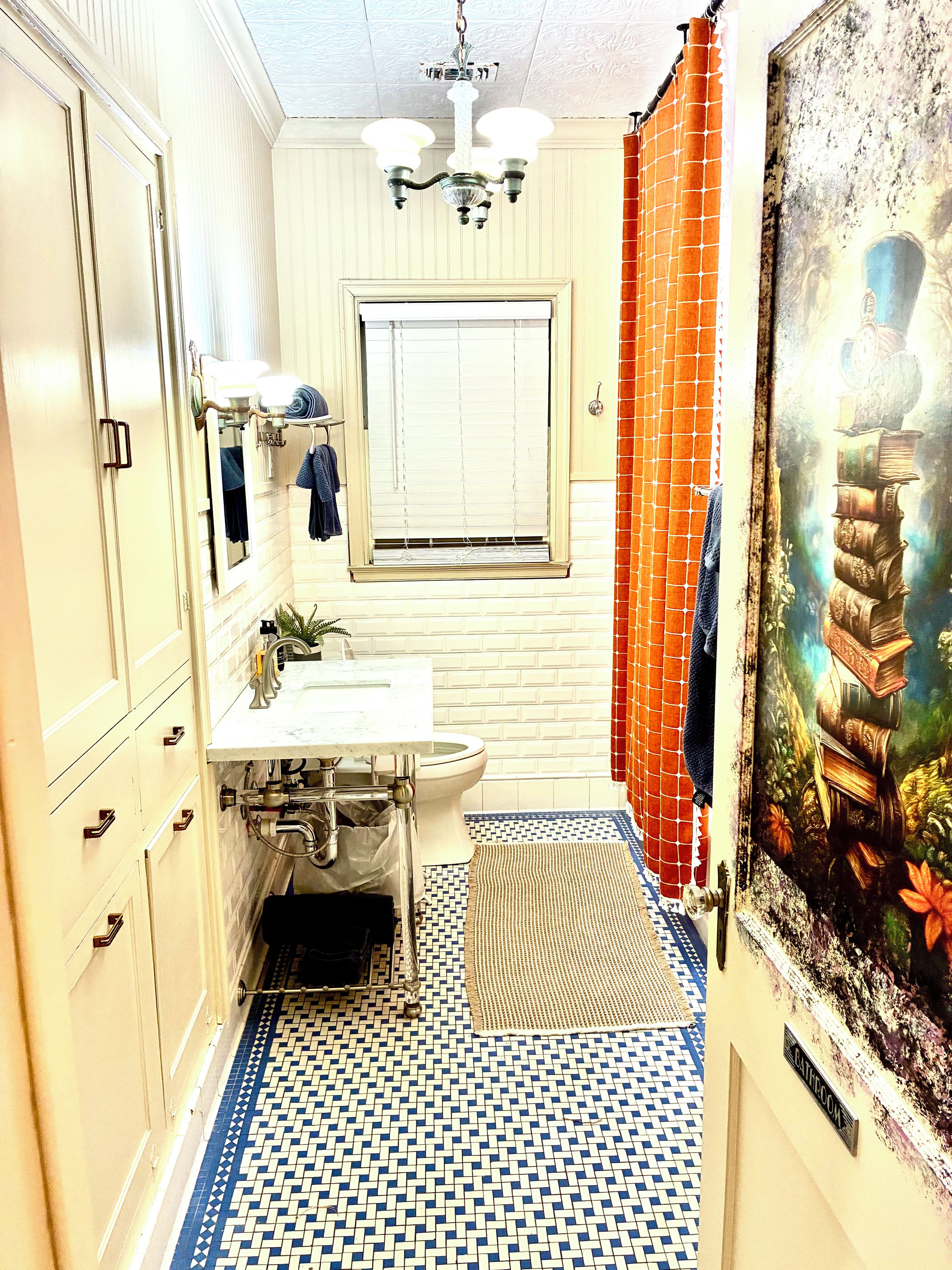 Un baño con piso de baldosas, lavamanos, inodoro y zona de ducha.