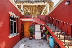 Ein rotes Gebäude mit einer Treppe, einer Holztür, einer Waschmaschine und einem Blumentopf.