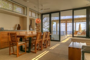 A modern interior with a dining area, large windows, and a view of the outdoors.