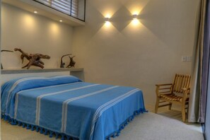 A bedroom with a bed, a wooden chair, and wall-mounted lights.