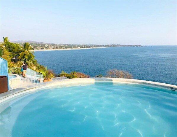 A swimming pool with a view of the sea and a distant shoreline.