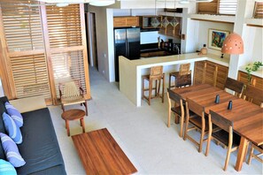 A modern kitchen with a central island, wooden furniture, and a dining area with a long table and chairs.