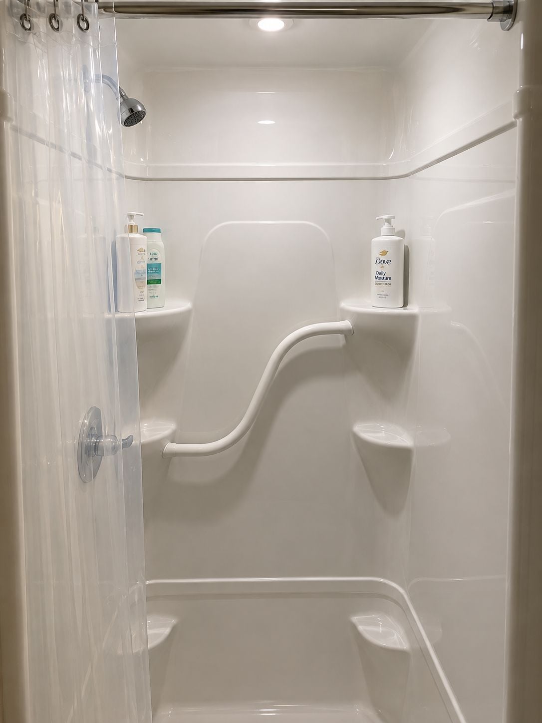Une douche équipée d’un pommeau de douche à main, d’un rideau transparent et d’une étagère pour les articles de toilette.