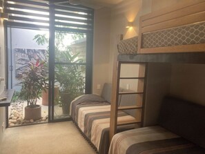 A compact room with bunk beds, a small table, and a potted plant.