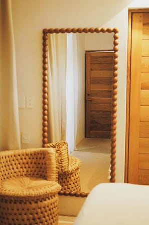 A room with a large mirror, a wicker chair, and a wooden door. - Cliffside villa w/ private pool (Puerto Escondido)