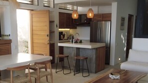 A modern kitchen with a central island, wooden cabinets, and a stainless steel refrigerator. - Minimalist villa w/ private pool (Puerto Escondido)