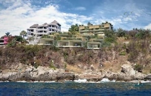 A coastal hotel with multiple buildings, some with balconies, overlooking the sea.