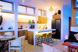 A compact kitchen with a central island, bar stools, and a dining area with a round table and chairs. - Sea-view villa w/ plunge pool (Puerto Escondido)