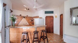 Eine Küche mit einem weißen Kühlschrank, Holz-Bodenhocker und einer gefliesten Spritzschutzwand.