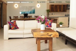 A living room with a sofa, a coffee table, and a dining area in the background. - Sea-view condo w/ 2 king suites (Puerto Escondido)