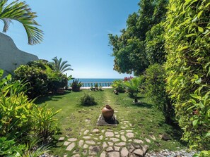 A garden pathway leading to a beach with a large vase in the center. - 🌊 Ocean-View Apartment with Spacious Terraces (Puerto Escondido)