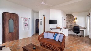 A living room with a sofa, a television, a stone wall, and a fireplace. - 🌊 Ocean-View Apartment with Spacious Terraces (Puerto Escondido)