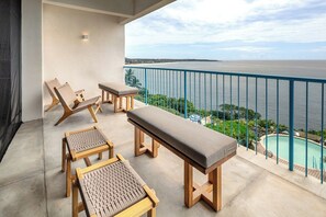 A balcony with wooden furniture and a view of a swimming pool and the sea. - Ocean-view condo w/ plunge pool (Puerto Escondido)