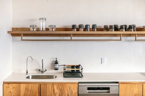 Kitchen counter with a sink, dish rack and open shelving. - Ocean-view condo w/ plunge pool (Puerto Escondido)