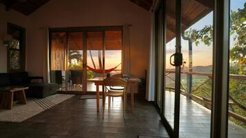 A room with a sliding glass door leading to a balcony, a wooden table, a chair, and a sofa.
