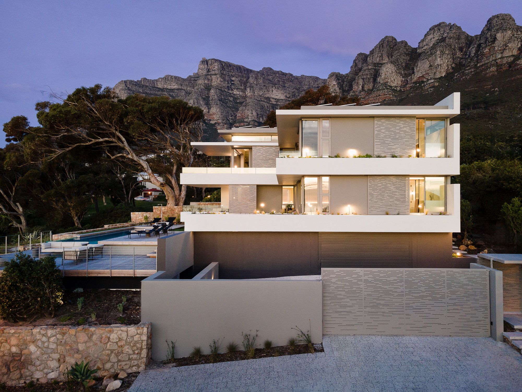 A modern multi-story house with a swimming pool and a view of mountains.