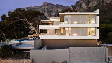 A modern multi-story house with a swimming pool and a view of mountains.