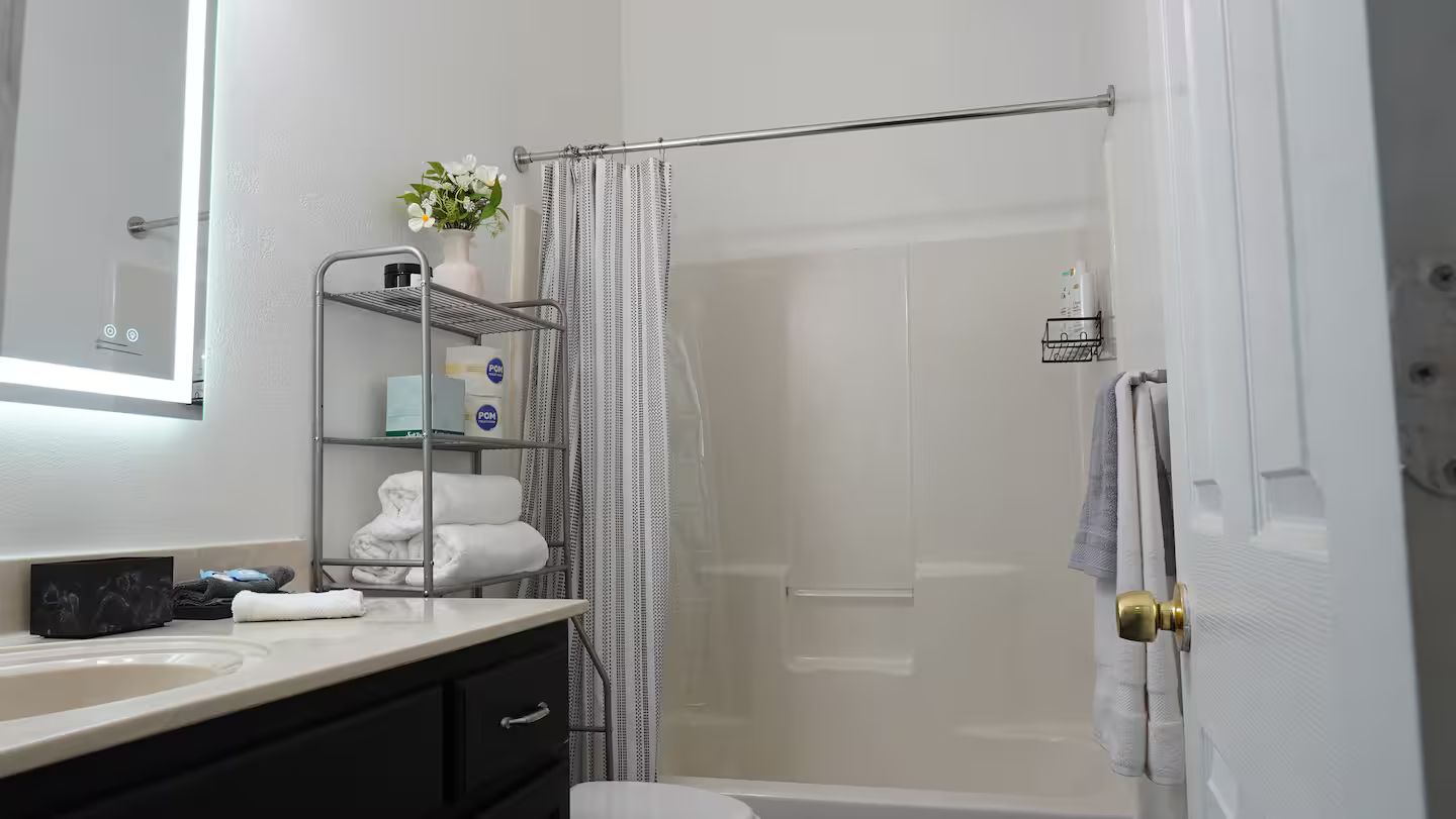 Un baño moderno con cabina de ducha de vidrio, tocador con espejo y barra para toallas.