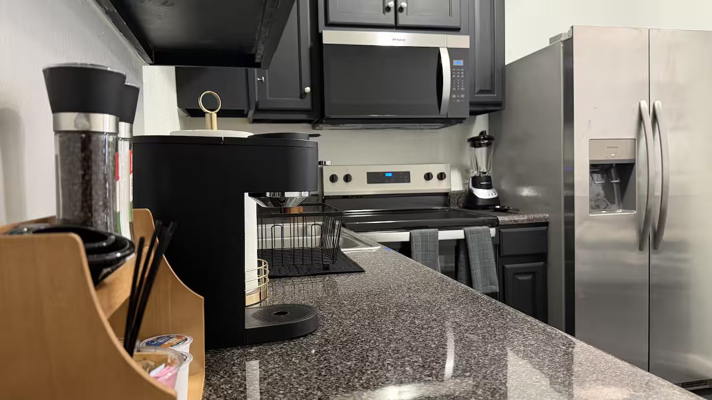 Una cocina con refrigerador de acero inoxidable, microondas y cafetera.