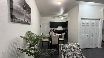 Un coin repas comprenant une table et des chaises, un ventilateur de plafond et une porte donnant sur la cuisine.
