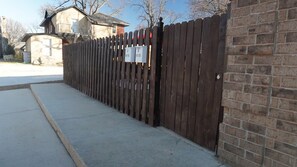 Ein von Zäunen und einer Backsteinmauer umschlossener Bereich mit einem Betonweg.