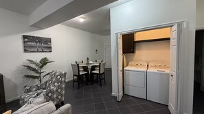 Un espacio habitable compacto con comedor, lavadora y una puerta que da a otra habitación.