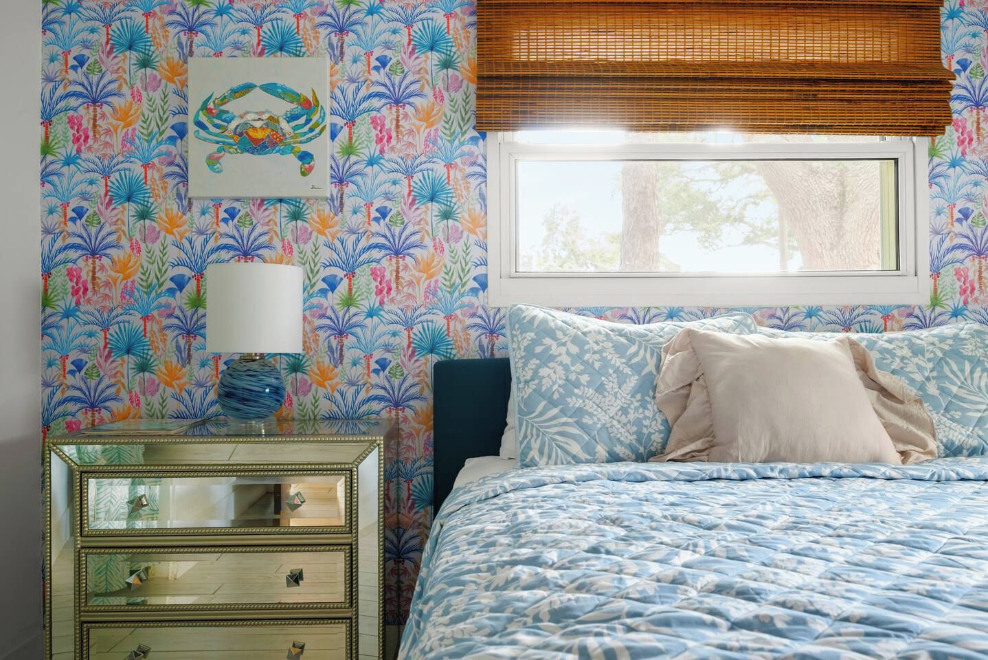 A bedroom with a bed, a nightstand, a lamp, and a window with blinds.