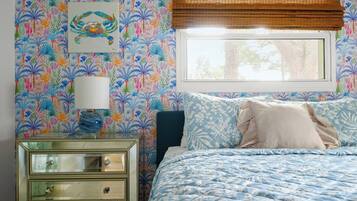 A bedroom with a bed, a nightstand, a lamp, and a window with blinds.