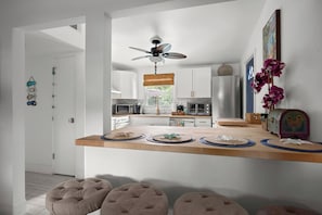 Cozinha moderna com ilha de madeira, eletrodomésticos de aço inoxidável e ventilador de teto.
