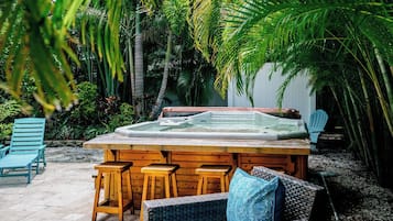 Un bain à remous entouré de meubles et de chaises en bois, dans un cadre de jardin tropical.