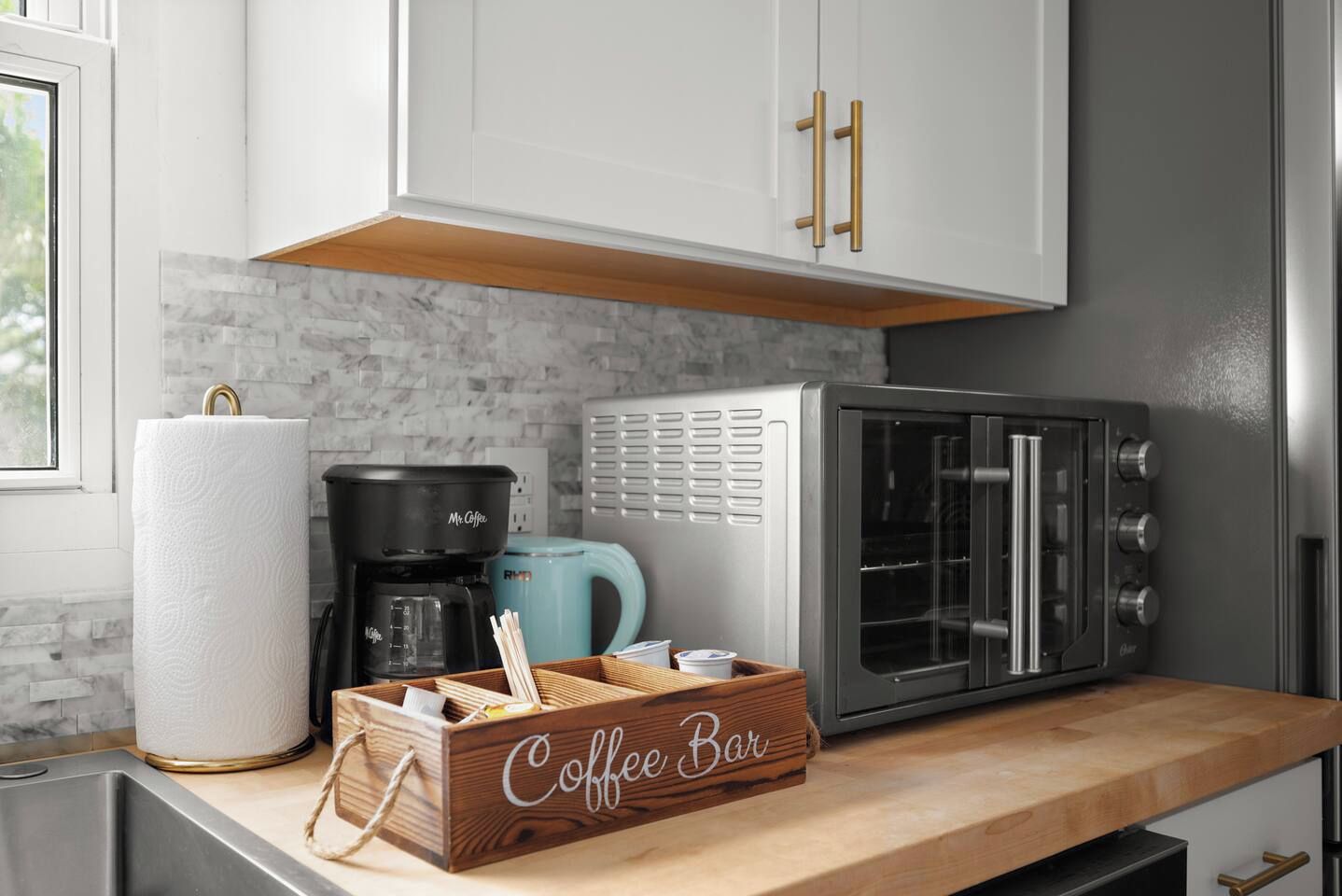A kitchen with a coffee maker, a toaster, and a coffee bar.