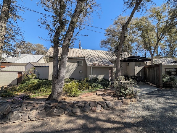 A residential property with a stone pathway, a covered patio, and a metal roof.