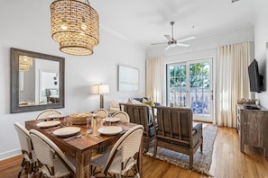 A dining area with a wooden table, wicker chairs, and a woven light fixture. - Village of South Walton F307- Vitamin Sea (Panama City Beach)