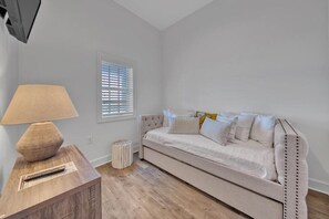 A room with a beige sofa, a lamp on a wooden side table, and a window with blinds. - Village of South Walton F307- Vitamin Sea (Panama City Beach)
