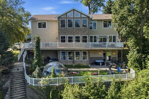 A two-story house with a covered patio area and a stone facade. - Lake House for 14 · Hot Tub, Fire Pit & Garden Dome · 18–20 min to Indiana Dunes National Park (Valparaiso)