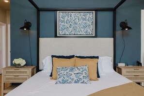 A bedroom with a bed, two bedside tables, a nightstand, a wall-mounted lamp, and a framed artwork above the bed. - Lake House for 14 · Hot Tub, Fire Pit & Garden Dome · 18–20 min to Indiana Dunes National Park (Valparaiso)