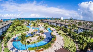 Un resort con piscina central, varias dependencias para huéspedes y vista al océano.