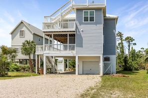 A two-story house with a covered porch, a garage, and a staircase leading to a balcony. - The Blue Pelican | Rooftop Deck & Gulf & Bay Views (Port St. Joe)