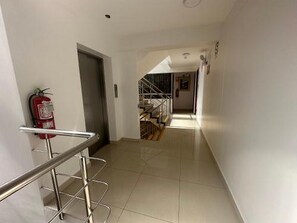 A corridor with a fire extinguisher mounted on the wall, a metal handrail, and a staircase in the distance. - Hotel Inka Palace Huayna Ccapac Cusco (Cusco)