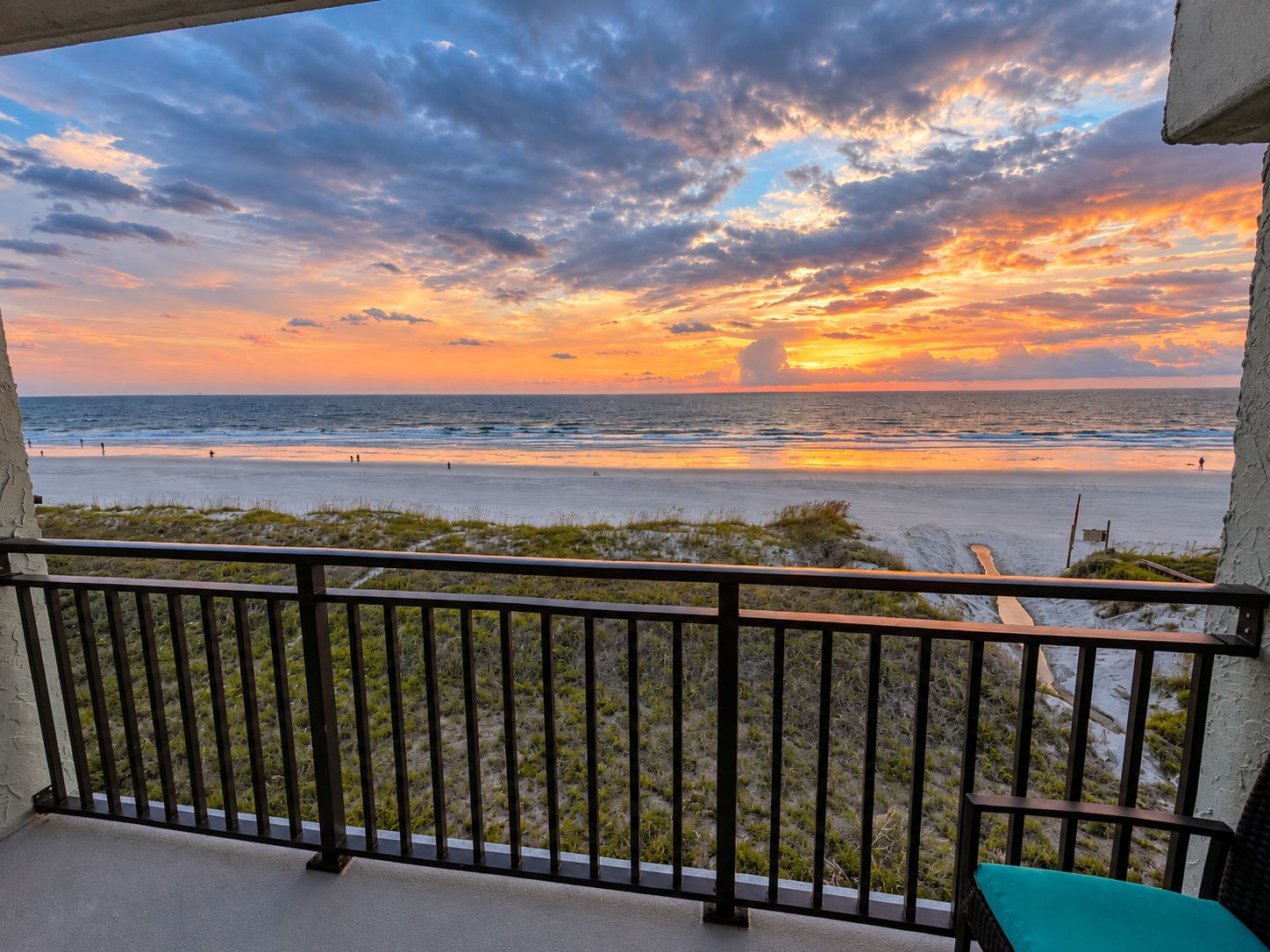 Un balcon avec vue sur la plage et l’océan au coucher du soleil.