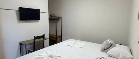 Habitación de hotel con cama, televisión de pantalla plana en la pared, escritorio y una silla.