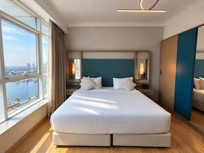Ein Hotelzimmer mit einem großen Bett, Blick auf eine Stadtlandschaft und einen Stadtfluss.