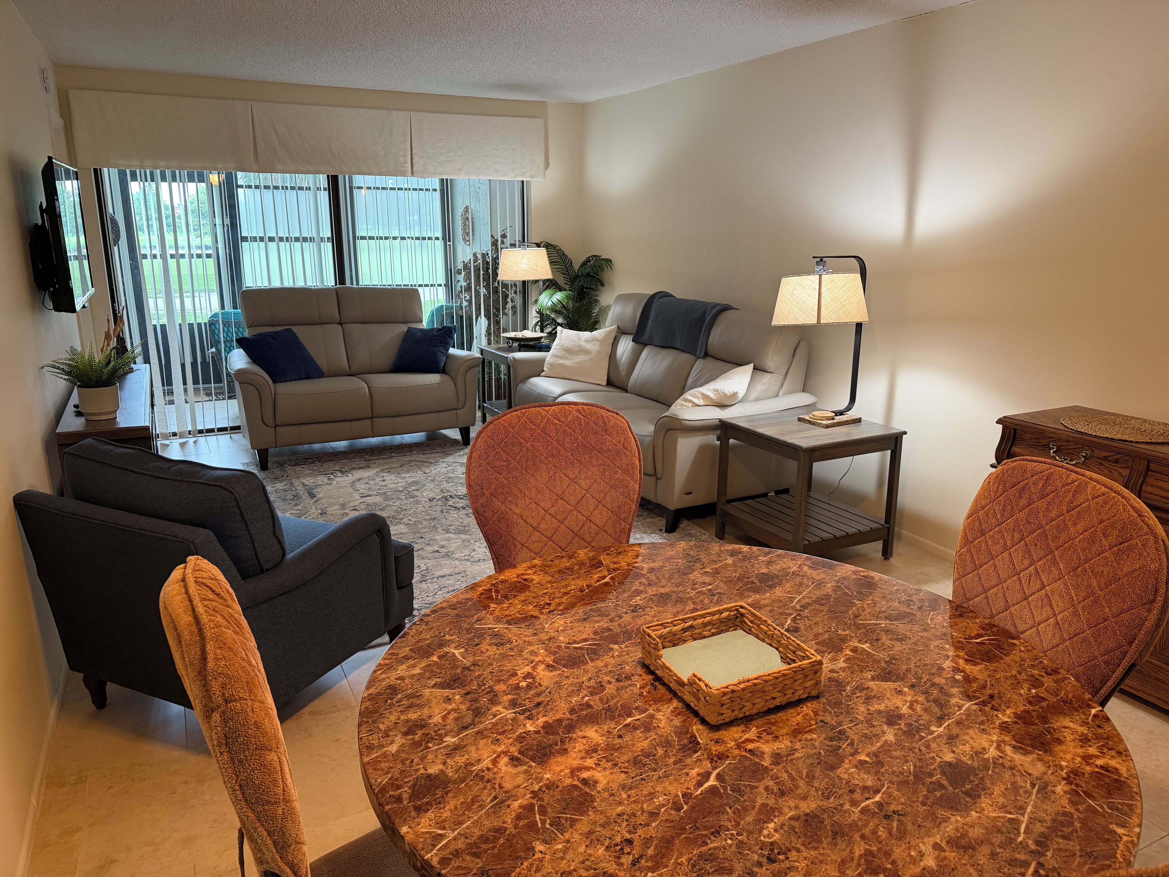 A living room with a round marble table, two sofas, a coffee table, and a lamp.