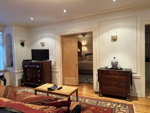 Een hotelkamer met een televisie, een houten dressoir, een bank en een kamerkleed met dessin.