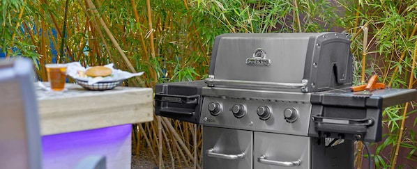 Un barbecue doté d’un écran numérique, d’un brûleur latéral et d’un panneau de commande avec des boutons.