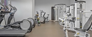 Ein Fitnessstudio mit verschiedenen Trainingsgeräten, darunter Laufbänder, Crosstrainer und Kraftgeräte.